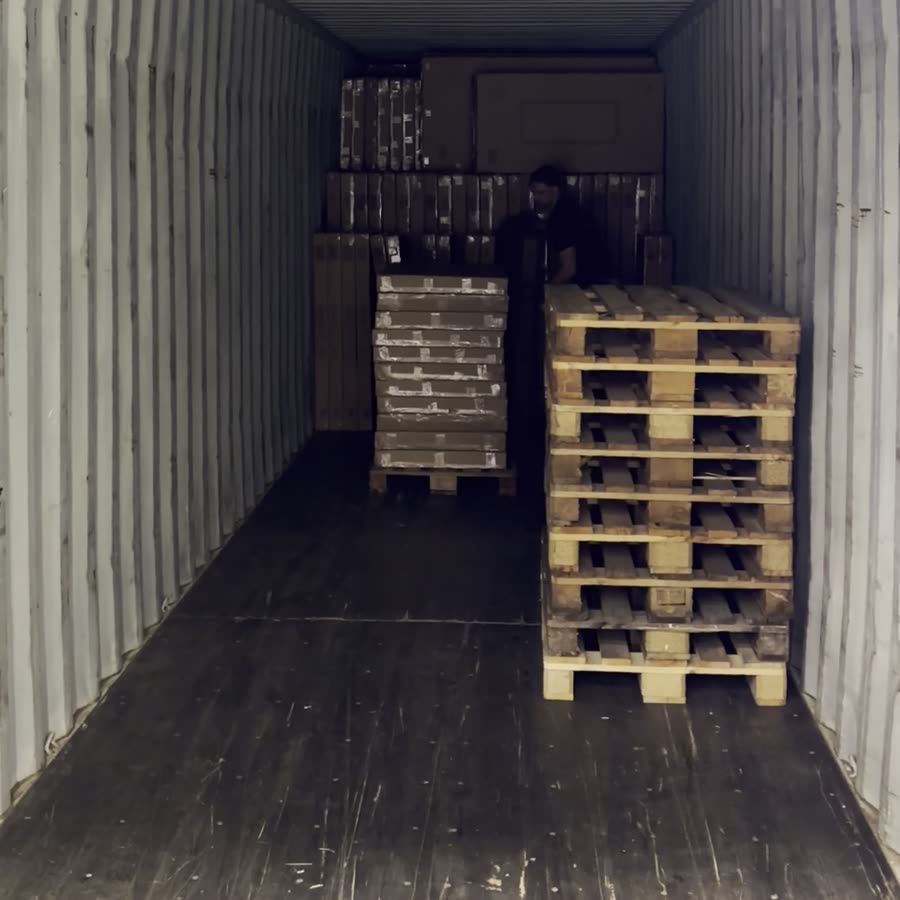 Een losteam in een zeecontainer met gestapelde pallets